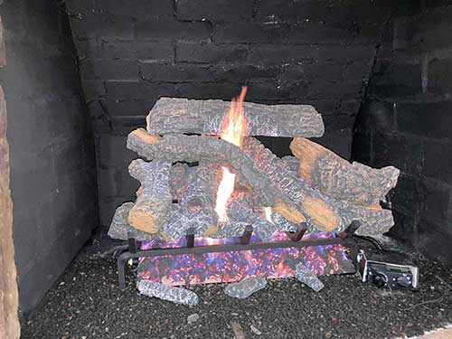 Stock photo of gas logs after installation - C and C Chimney After gas logs are installed with a fire and controls on the front