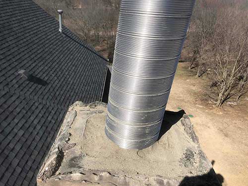 Stock photo of relining in progress - C and C Chimney Chimney during relining - long stainless steel liner sticking out of the top